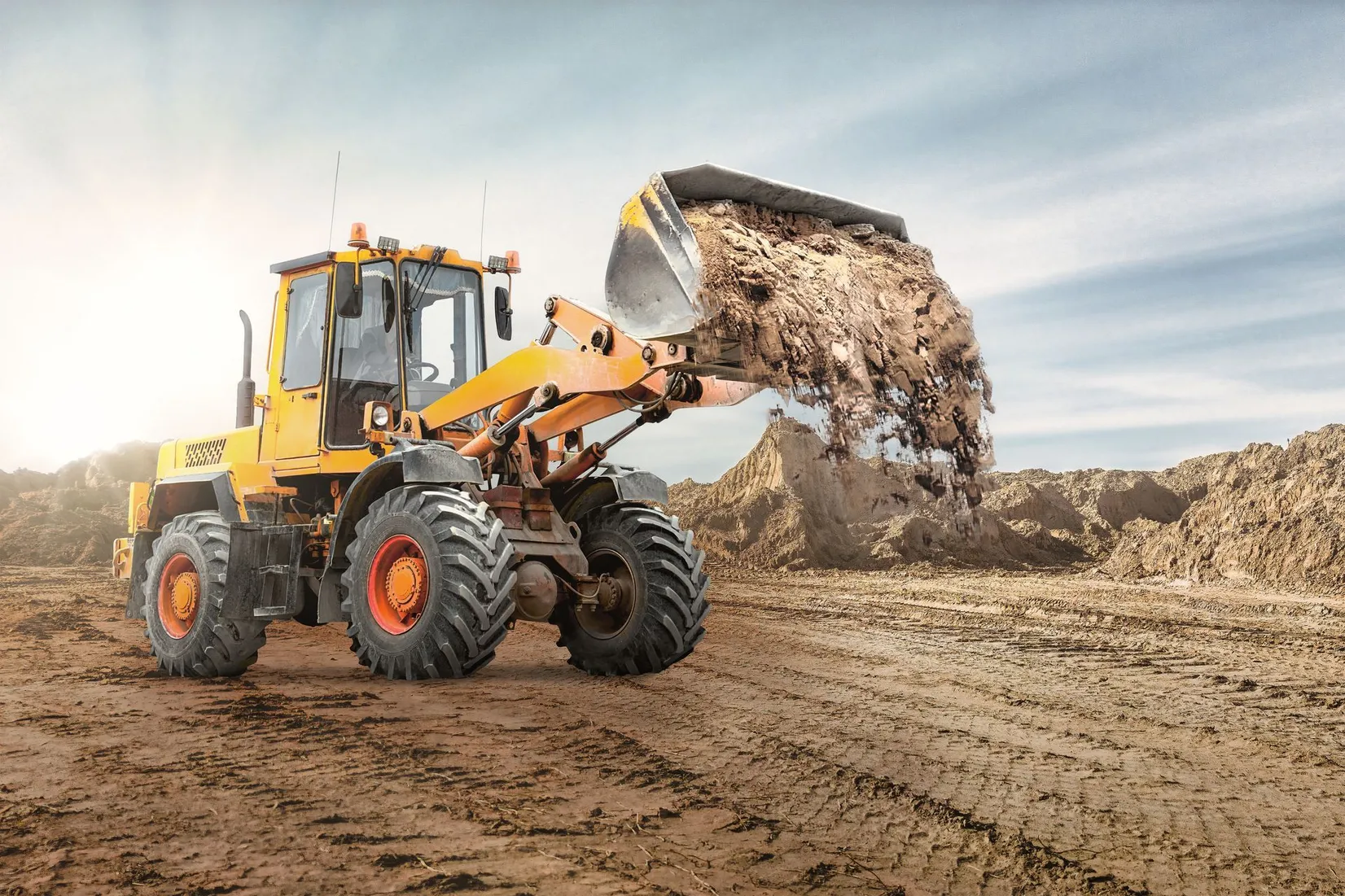 A bulldozer is loading dirt into a bucket at a construction site.